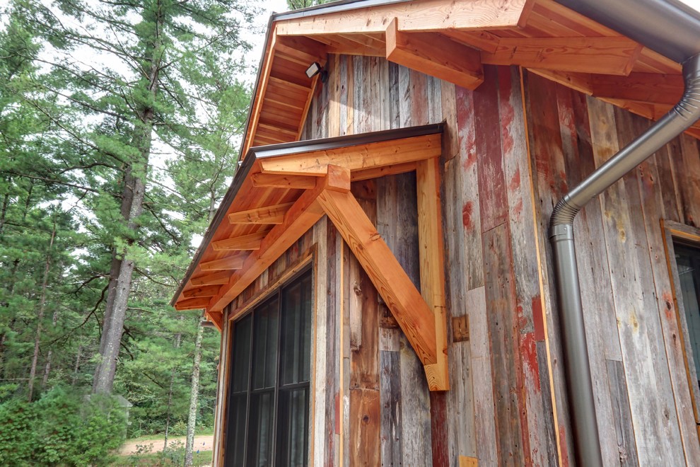 Foto de fachada de casa rural de dos plantas con revestimiento de madera, tejado a dos aguas y tejado de metal