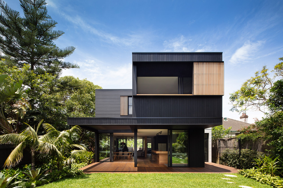 Large and black contemporary two floor detached house in Melbourne with a flat roof and a metal roof.