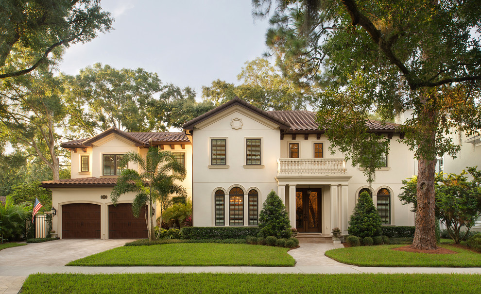 Large and beige mediterranean two floor render house exterior in Tampa with a pitched roof.