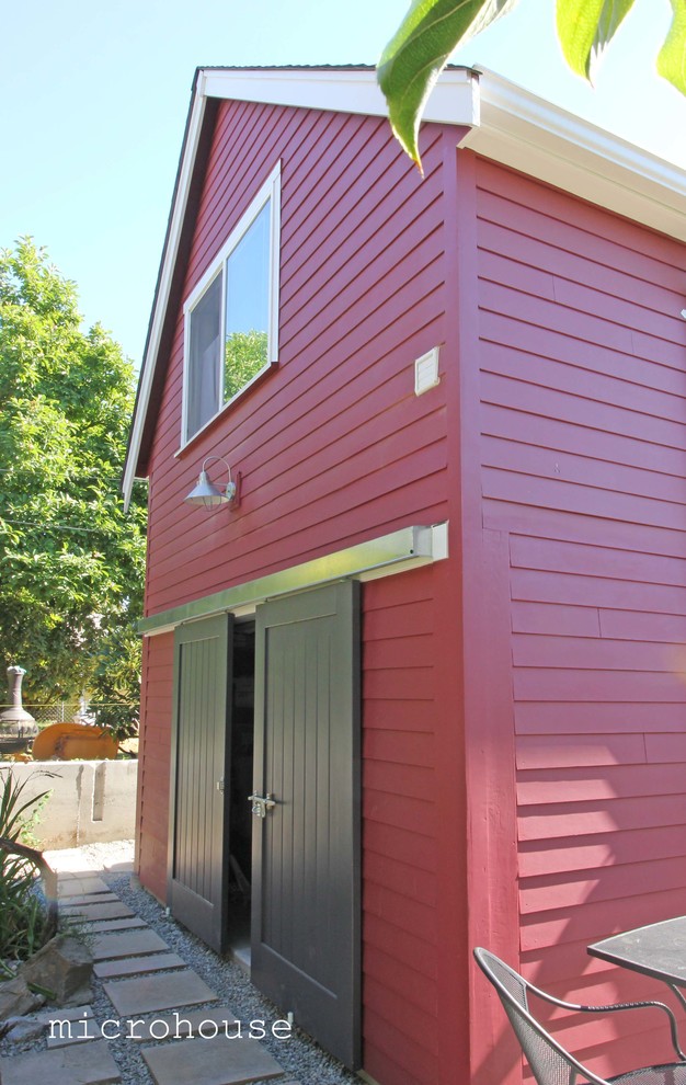Inspiration för ett litet funkis rött hus, med två våningar, fiberplattor i betong och sadeltak
