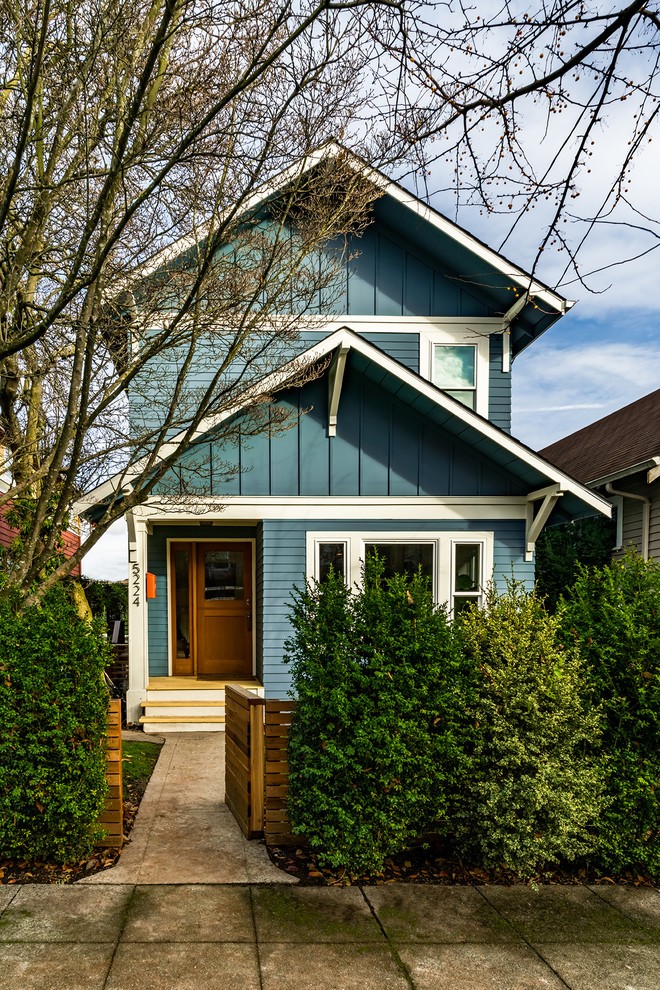 Пример оригинального дизайна: двухэтажный, синий частный загородный дом среднего размера в стиле кантри с облицовкой из ЦСП, двускатной крышей и крышей из гибкой черепицы