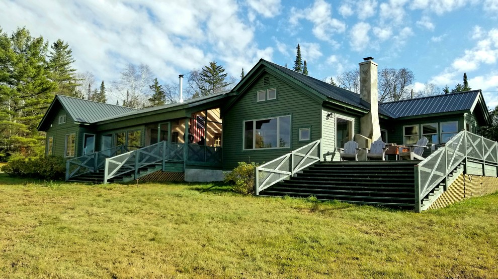 Idée de décoration pour une façade de maison verte vintage en bois de taille moyenne et de plain-pied avec un toit à deux pans et un toit en métal.
