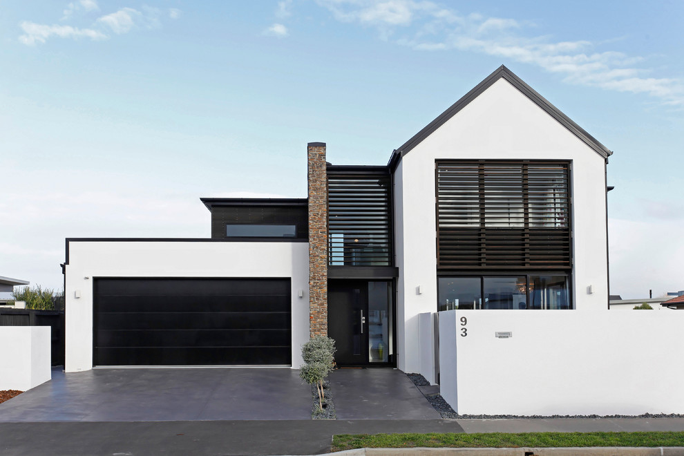 Réalisation d'une façade de maison blanche nordique en stuc à niveaux décalés.