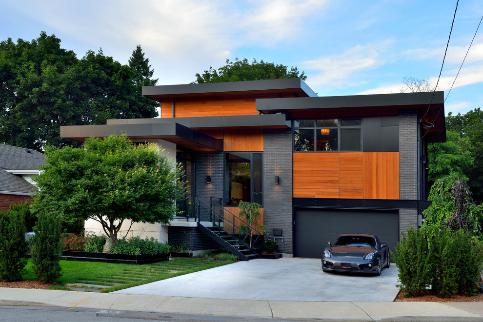 Cette photo montre une grande façade de maison grise tendance à un étage avec un revêtement mixte et un toit plat.