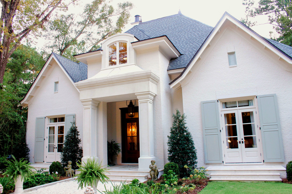Aménagement d'une façade de maison blanche classique en brique à un étage avec un toit en shingle.