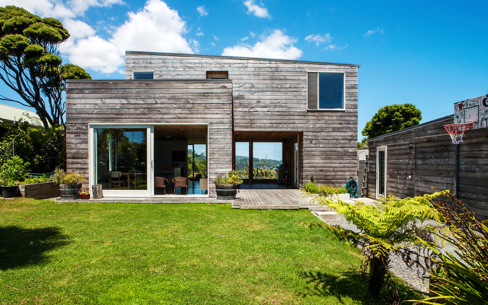 Gey rustic two floor house exterior in Auckland with wood cladding and a lean-to roof.