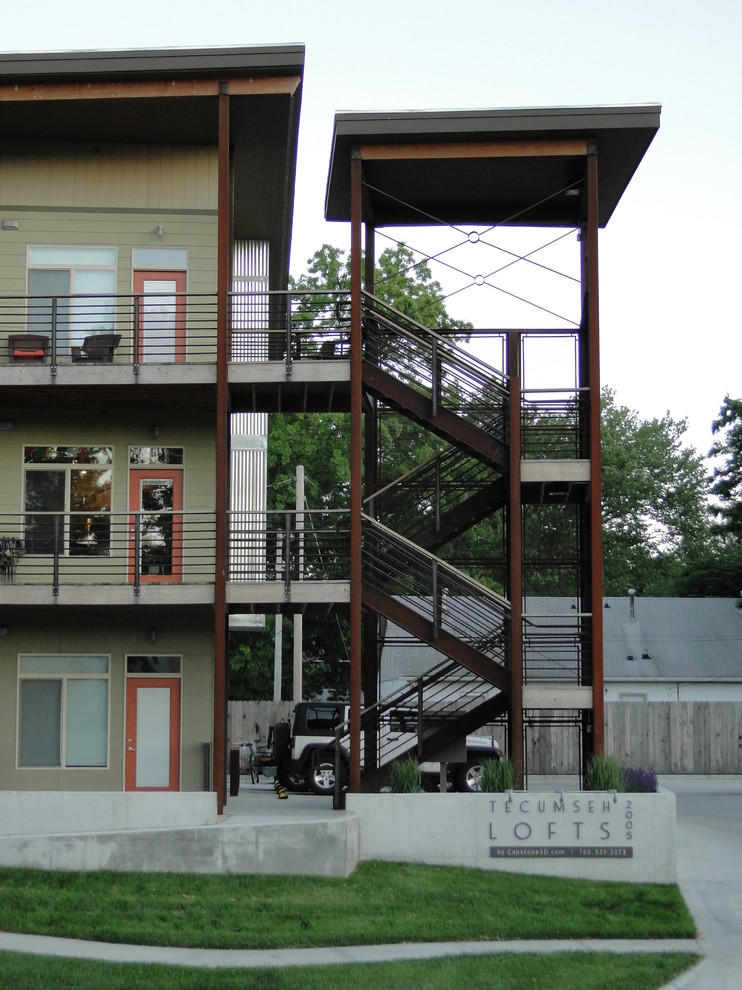 Bild på ett litet industriellt grönt hus, med tre eller fler plan och fiberplattor i betong