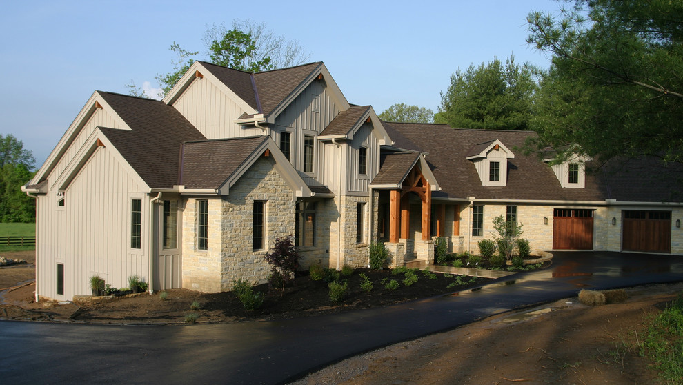 На фото: большой, двухэтажный, бежевый дом в стиле кантри с облицовкой из камня и двускатной крышей с