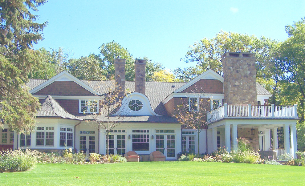 Esempio della facciata di una casa marrone a tre piani con rivestimenti misti e tetto a mansarda