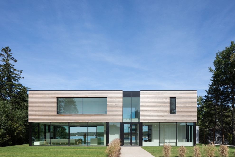 Aménagement d'une façade de maison beige moderne en bois à un étage avec un toit plat.