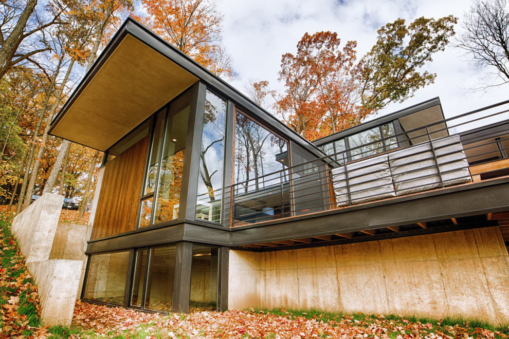 Cette image montre une petite façade de maison marron minimaliste en bois à un étage avec un toit plat.