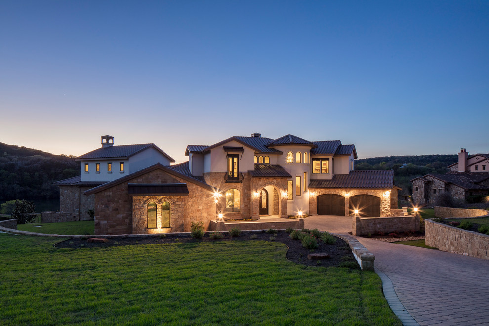 Example of a huge tuscan multicolored two-story stone exterior home design in Austin with a hip roof