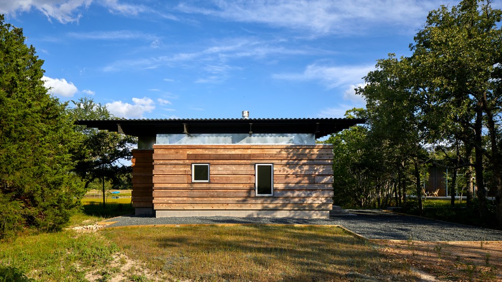 Cette photo montre une petite façade de maison chic de plain-pied avec un revêtement mixte, un toit en appentis et un toit en métal.