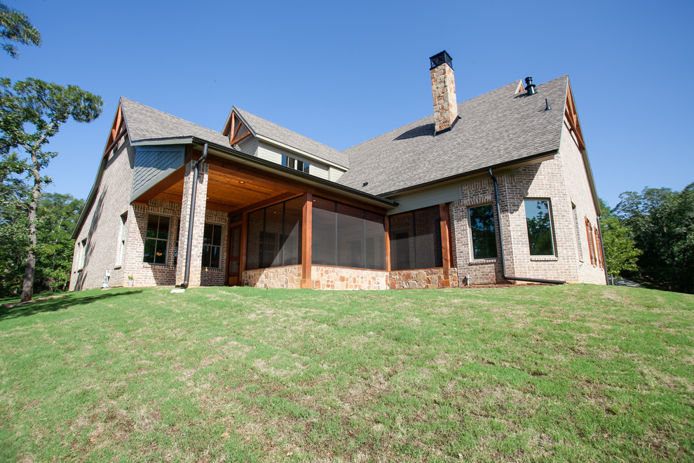 Design ideas for a large and red rustic two floor brick house exterior in Dallas with a half-hip roof.