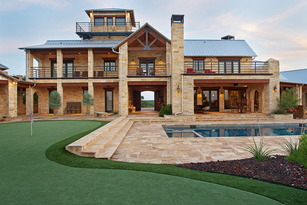 Inspiration for a huge rustic beige two-story stone exterior home remodel in Dallas with a metal roof