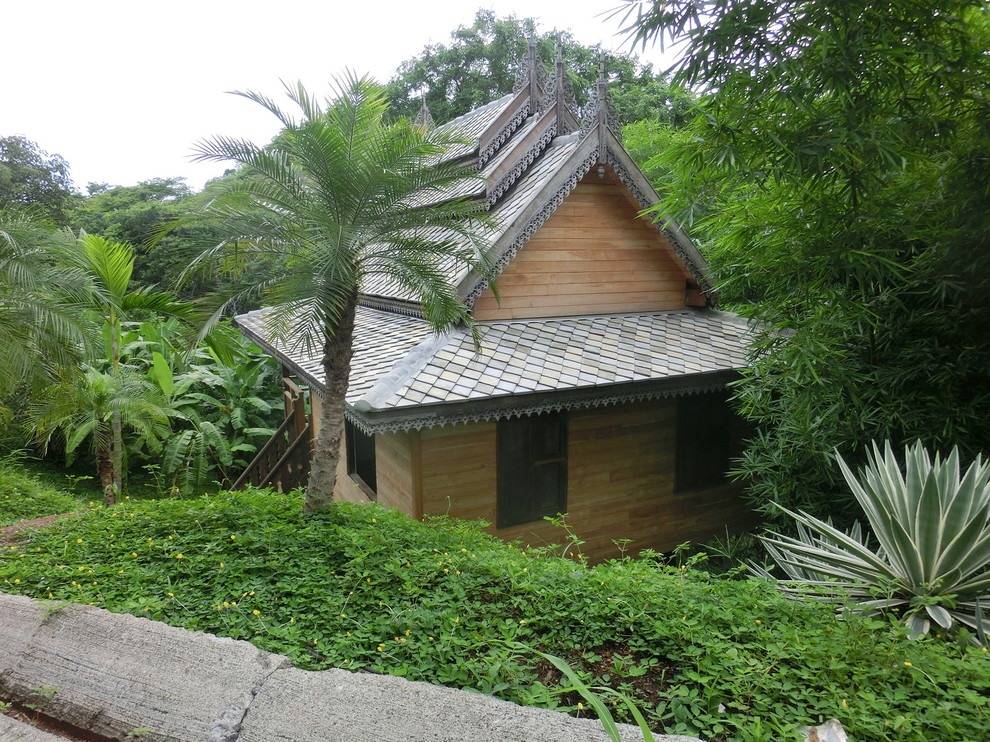 Foto della facciata di una casa piccola gialla etnica a un piano con rivestimento in legno