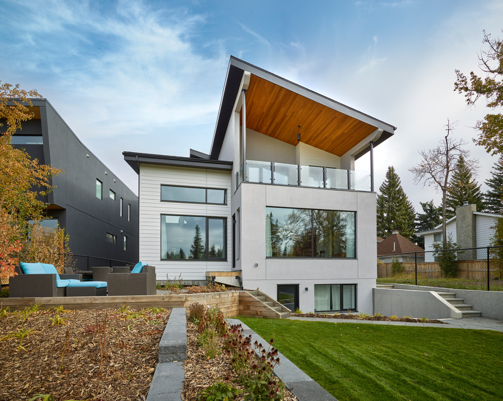 Cette photo montre une façade de maison grise tendance à deux étages et plus avec un revêtement mixte et un toit plat.