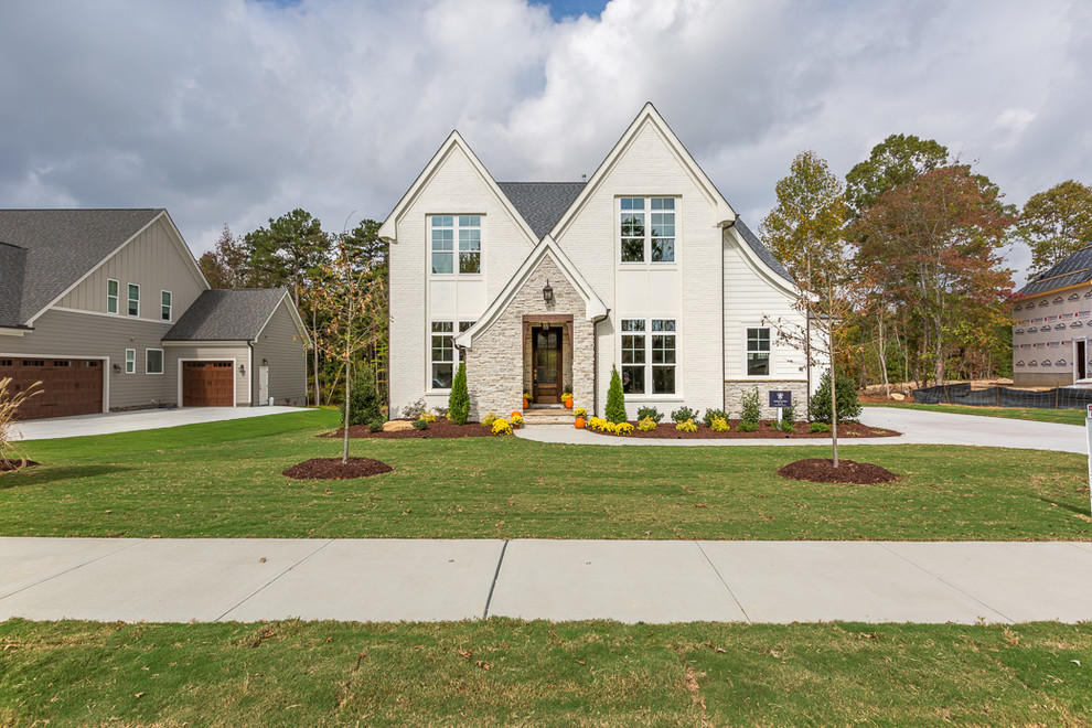 Mid-sized cottage white two-story brick exterior home photo in Raleigh with a shingle roof