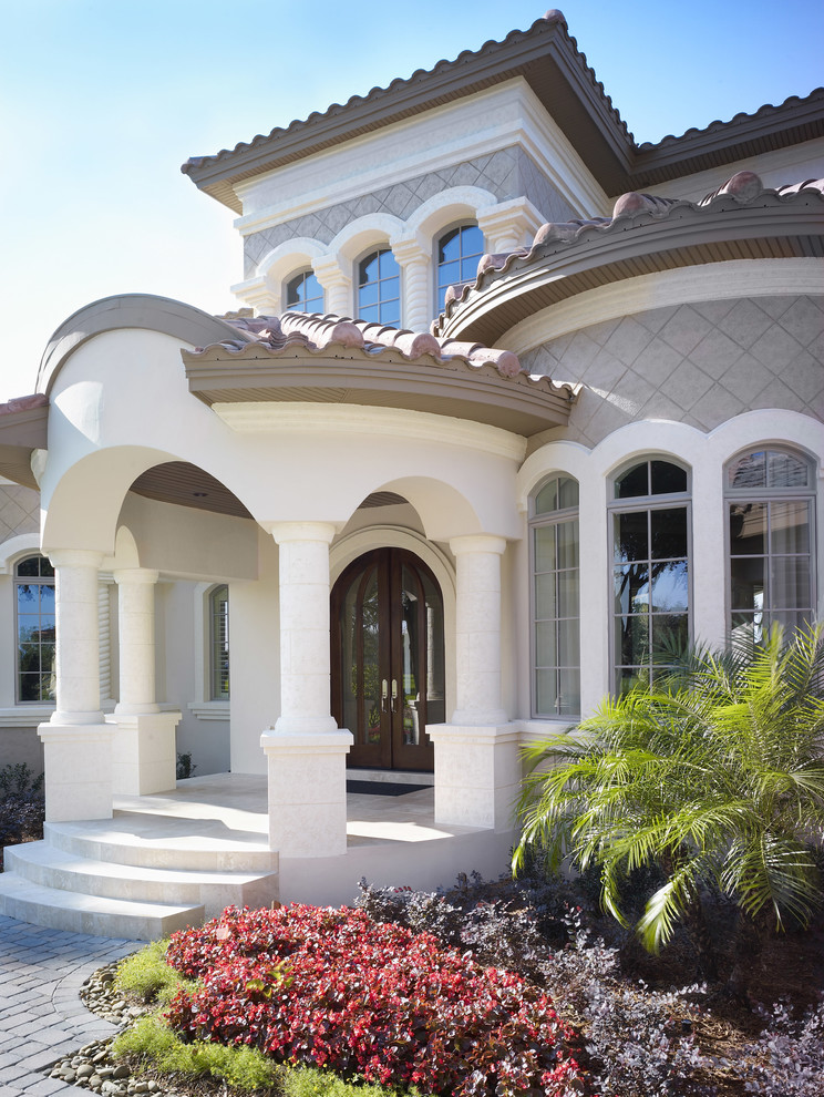 Стильный дизайн: большой, двухэтажный, серый частный загородный дом в средиземноморском стиле с облицовкой из цементной штукатурки, вальмовой крышей и черепичной крышей - последний тренд