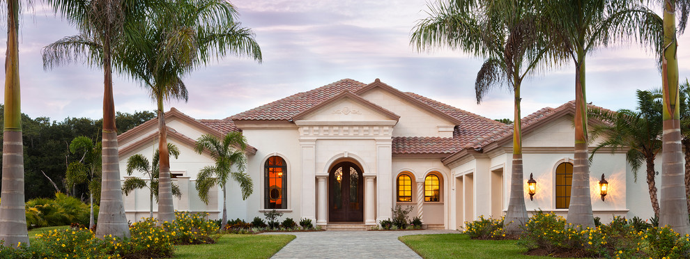 Expansive and beige mediterranean bungalow house exterior in Tampa with stone cladding.