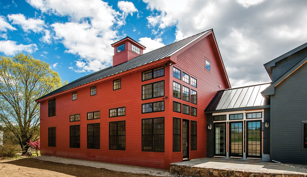 Imagen de fachada roja moderna grande de tres plantas con revestimiento de madera y tejado a dos aguas