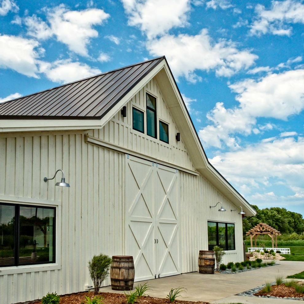 Immagine della facciata di una casa ampia bianca country a due piani con rivestimento in legno, tetto a capanna e copertura in metallo o lamiera