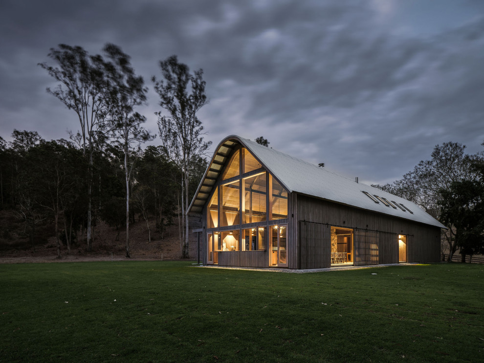 Cette photo montre une façade de maison nature en bois de taille moyenne et à un étage avec un toit à deux pans et un toit en métal.