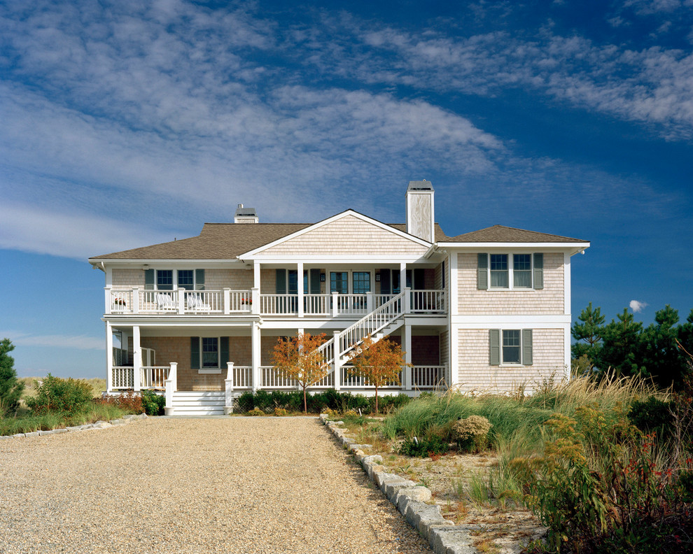 Imagen de fachada beige costera grande de dos plantas con tejado a cuatro aguas