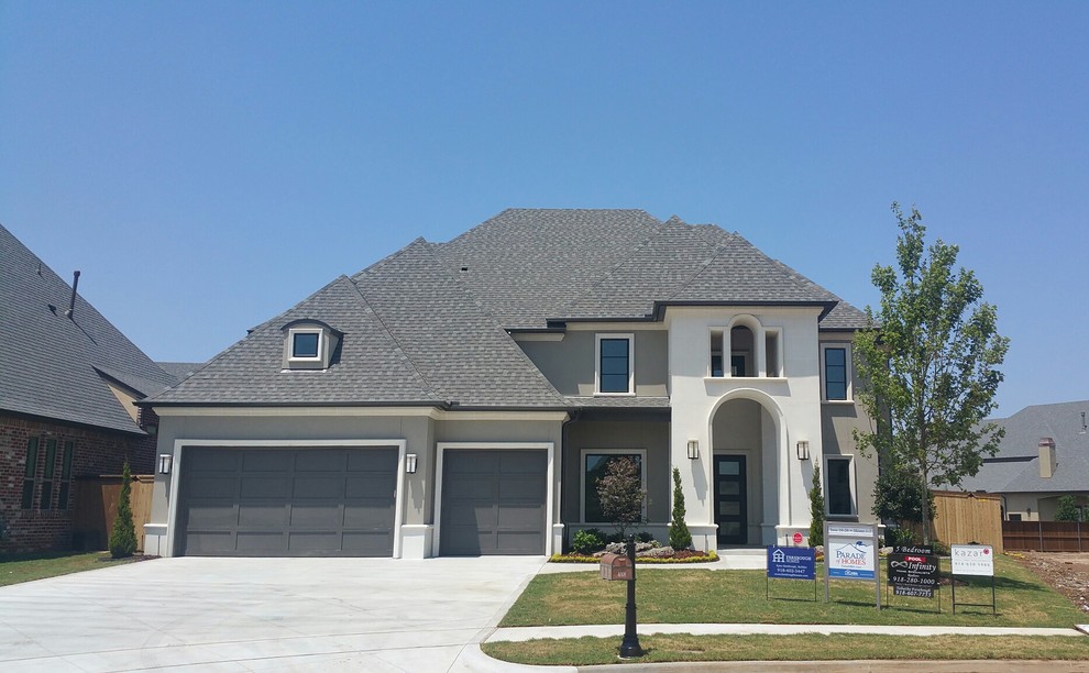 Example of a mid-sized transitional gray two-story stucco house exterior design in Other with a hip roof and a shingle roof