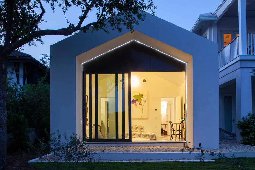 Photo of a small and white contemporary bungalow house exterior in Miami with wood cladding and a pitched roof.