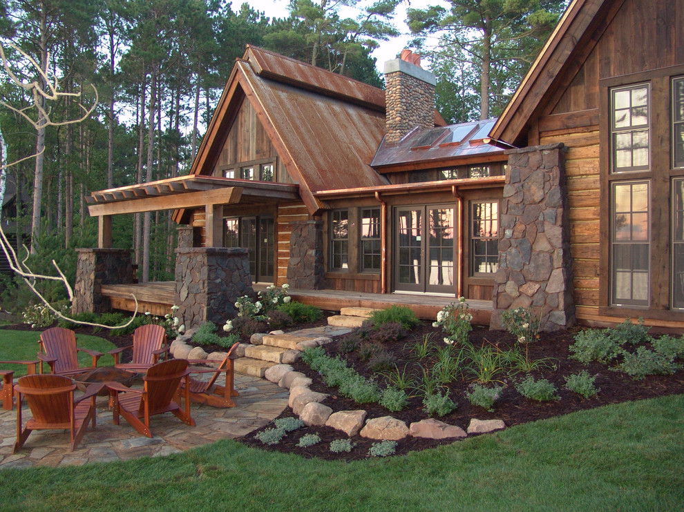 Imagen de fachada de casa marrón rural de tamaño medio de una planta con revestimiento de madera, tejado a dos aguas y tejado de metal