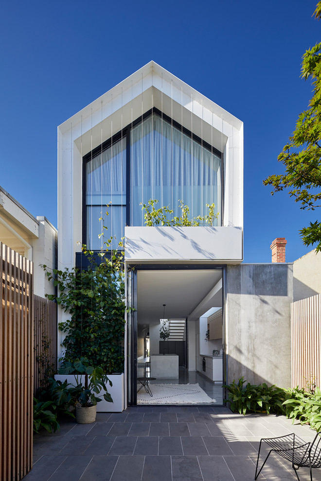 Cette image montre une façade de maison blanche design en verre à un étage avec un toit à deux pans et un toit en métal.