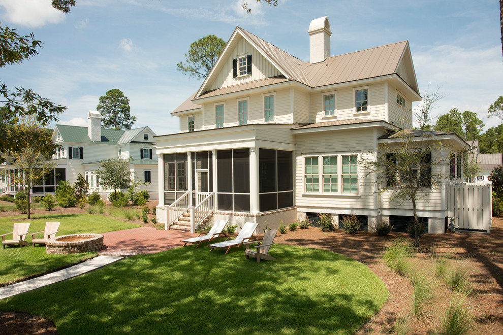 Cette photo montre une façade de maison blanche chic en bois de taille moyenne et à un étage avec un toit en métal.