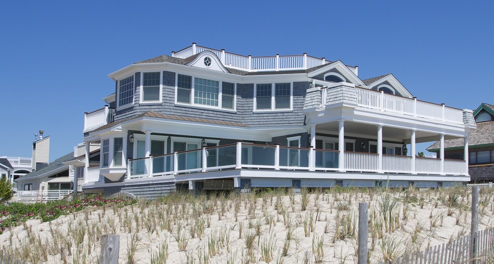 Пример оригинального дизайна: огромный, трехэтажный, деревянный, серый дом в морском стиле с двускатной крышей