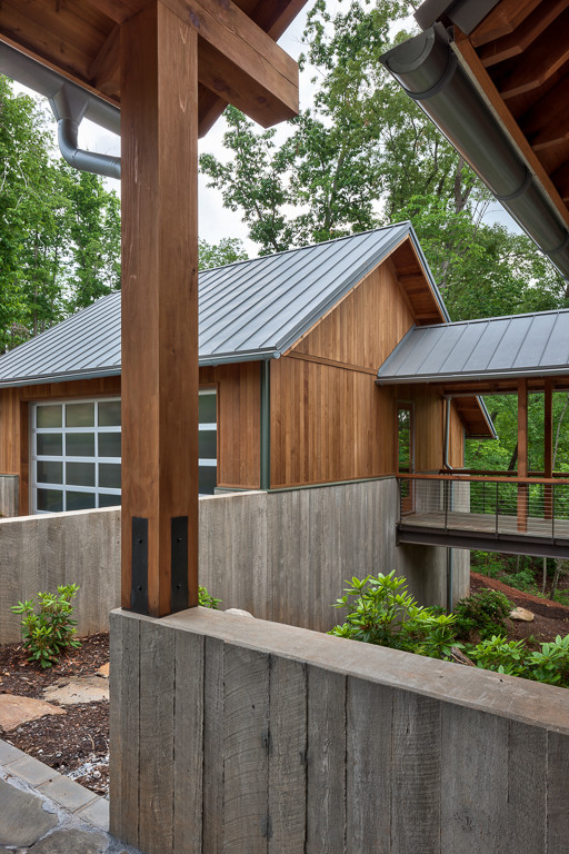 Réalisation d'une grande façade de maison marron design en bois à un étage avec un toit à quatre pans et un toit en métal.