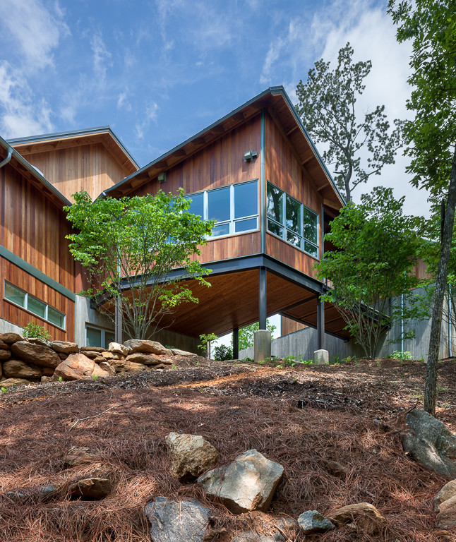 Idées déco pour une grande façade de maison marron contemporaine en bois à un étage avec un toit à quatre pans et un toit en métal.