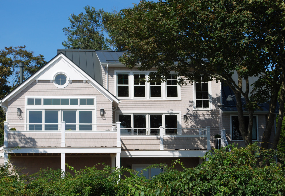 На фото: большой, двухэтажный, деревянный частный загородный дом в морском стиле с двускатной крышей и металлической крышей