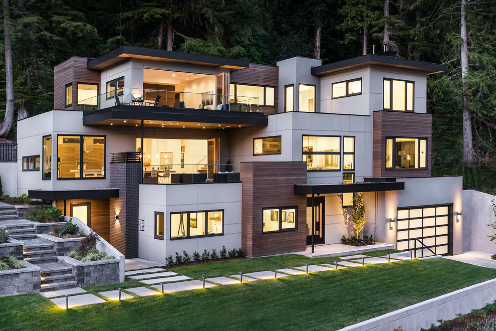This is an example of a large contemporary detached house in Vancouver with three floors, mixed cladding, a flat roof and a mixed material roof.