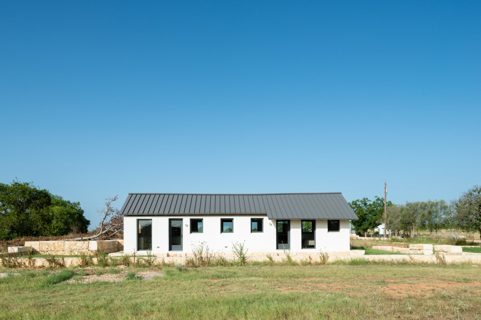 Idée de décoration pour une petite façade de Tiny House blanche sud-ouest américain en stuc de plain-pied avec un toit à deux pans, un toit en métal et un toit gris.