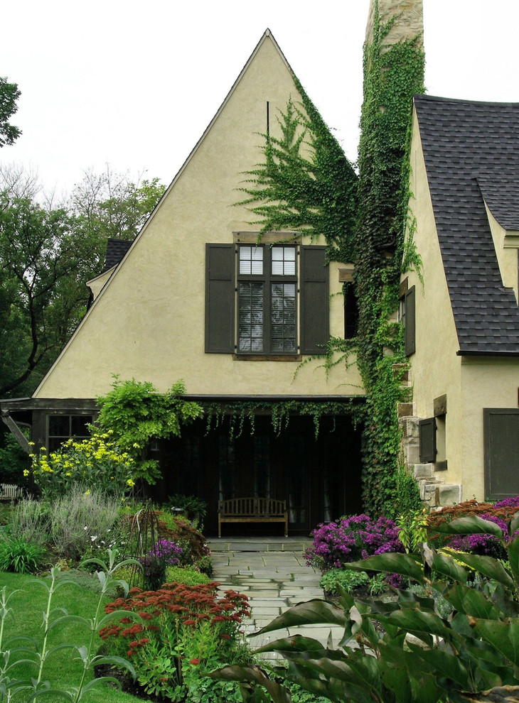 Пример оригинального дизайна: большой, двухэтажный, желтый частный загородный дом в классическом стиле с облицовкой из бетона, полувальмовой крышей и крышей из гибкой черепицы