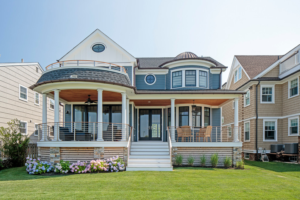 Ejemplo de fachada de casa azul costera de dos plantas con revestimientos combinados, tejado a dos aguas y tejado de teja de madera