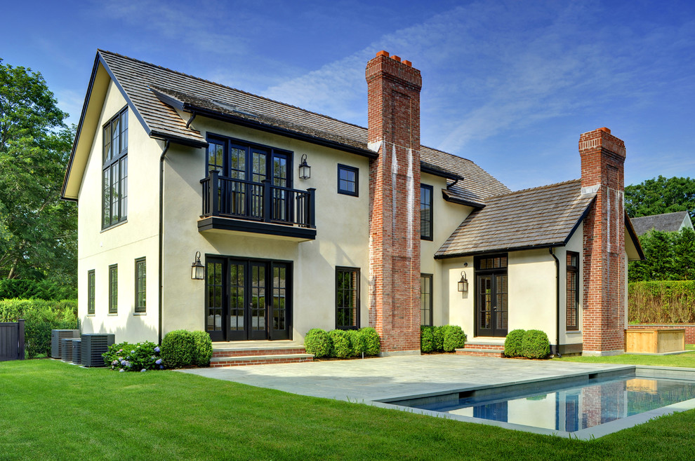 Inspiration for a large timeless beige two-story stucco gable roof remodel in Manchester