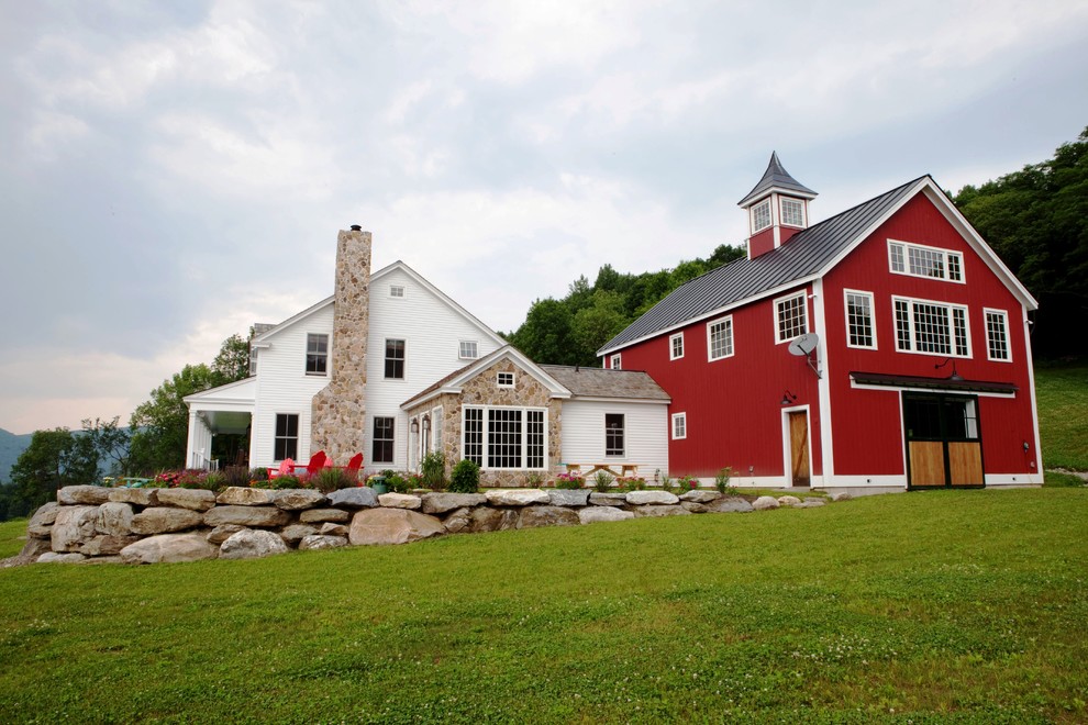 Cette photo montre une grande façade de maison rouge nature en bois à un étage avec un toit à deux pans et un toit en métal.