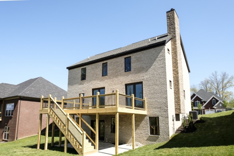 На фото: двухэтажный, серый дом среднего размера в стиле кантри с облицовкой из камня и двускатной крышей с