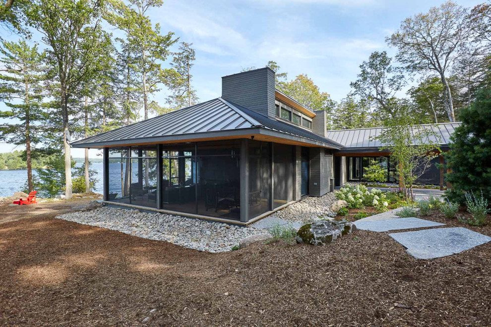 Inspiration pour une façade de maison grise chalet en verre de taille moyenne et de plain-pied avec un toit à quatre pans et un toit en métal.