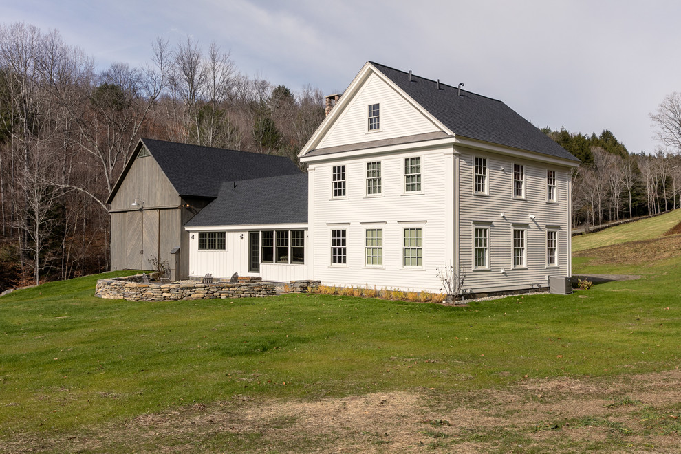 На фото: большой, белый дом в стиле кантри с облицовкой из винила и двускатной крышей с