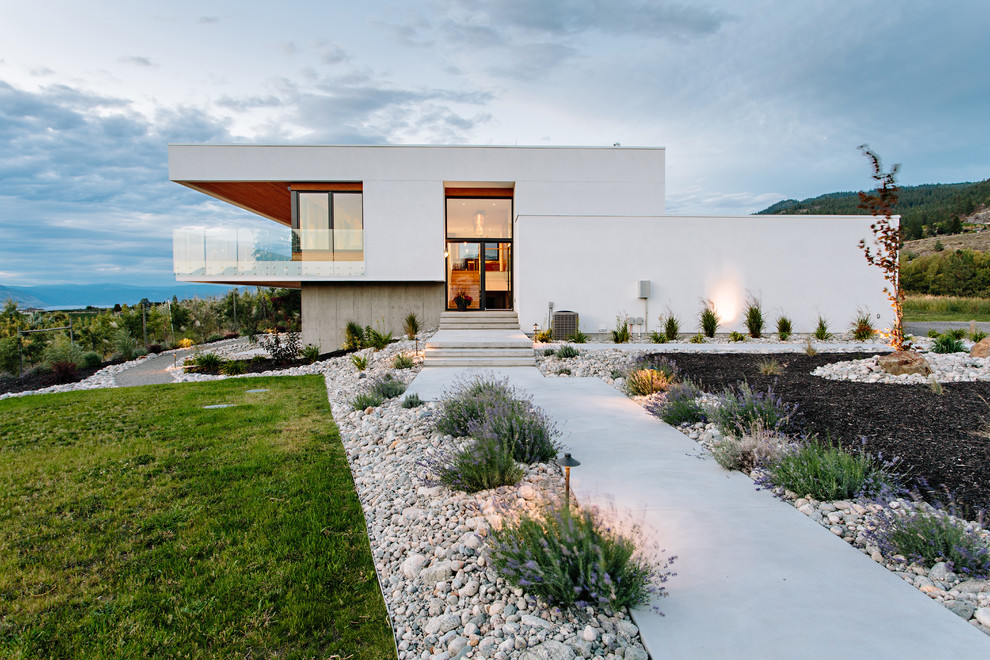 Imagen de fachada de casa blanca moderna a niveles con revestimiento de estuco y tejado plano