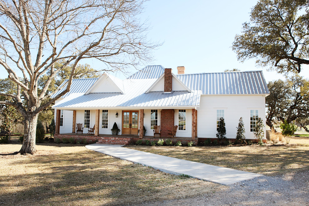 Example of a mid-sized farmhouse white one-story exterior home design in Austin