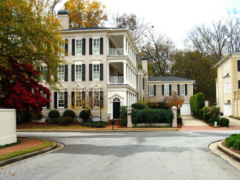 Photo of a large and beige traditional render house exterior in Atlanta with three floors and a hip roof.