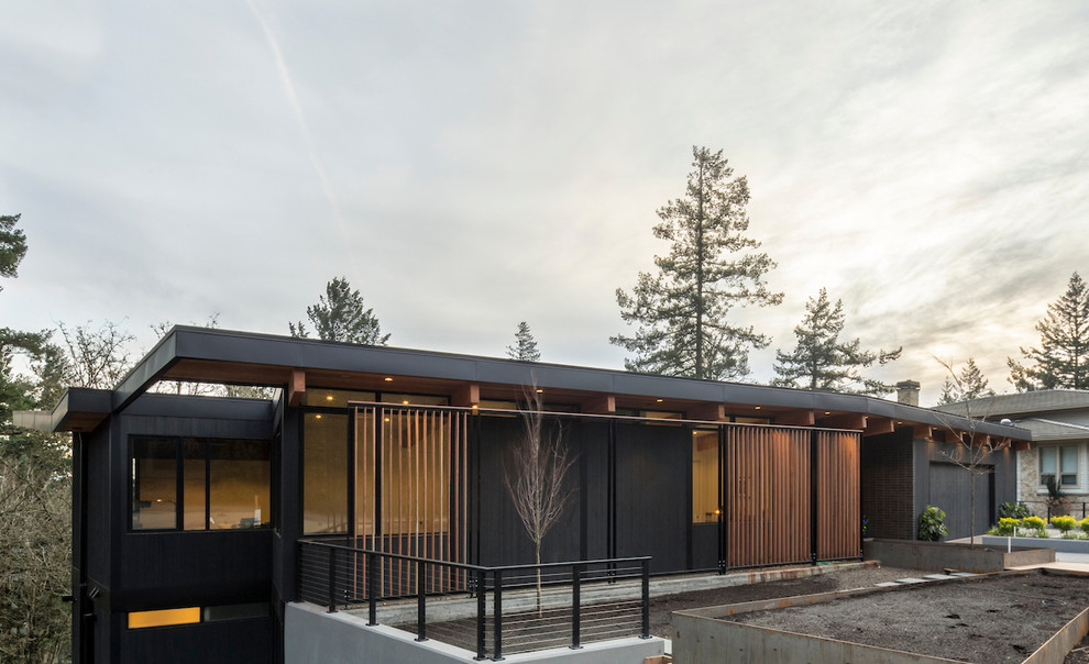 Inspiration pour une grande façade de maison noire vintage en bois à un étage avec un toit plat.